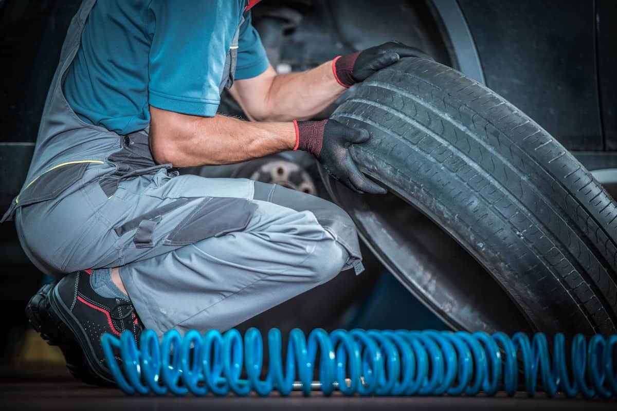 mechanic lifting a used automobile tire